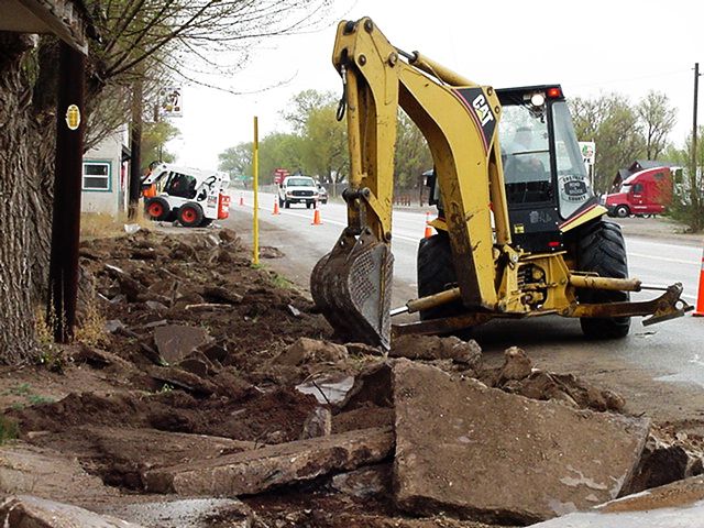 Backhoe at work removing old sidewalk